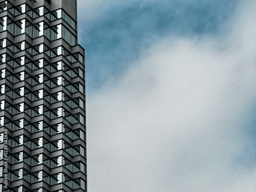 Aufkleber a modern skyscraper's geometric facade is sharply defined against a partly cloudy sky. the contrast 
