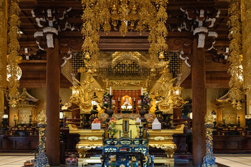 A breathtaking view of a Japanese Buddhist temple's golden interior, filled with intricate details and a serene atmosphere.