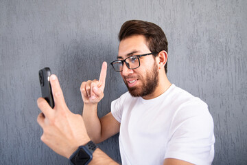 Joven apuesto teniendo una videollamada. Hombre con barba y anteojos usando su teléfono celular 