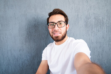 Joven sonriente tomándose una selfie. Hombre con barba sonriendo a la cámara 