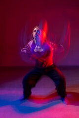 Young woman dancing modern dances in red blue neon light. Vertical photo.