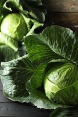 Fototapeta premium Ripe cabbages on black wooden table, closeup