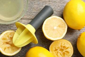 Plastic juicer and fresh lemons on grey wooden table, flat lay