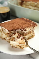 Piece of tasty tiramisu on white marble table, closeup