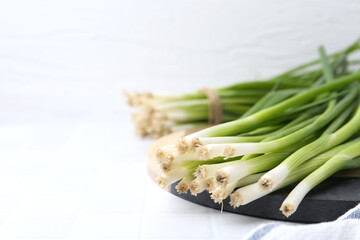 Fresh green onions on white table, closeup. Space for text