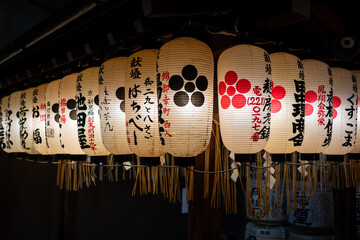 Glowing Japanese lanterns with elegant calligraphy illuminate a festive night scene, showcasing...