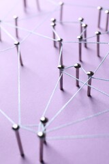 Network connection. Nails linked together by thread on violet background, closeup