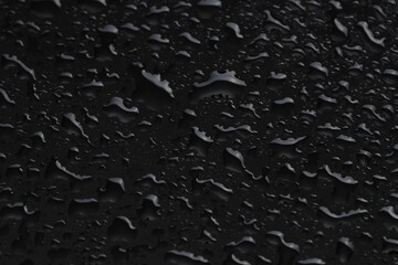 Water drops on black glass surface, closeup