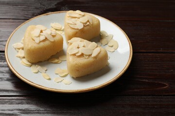Pieces of delicious semolina halva with almond flakes on wooden table