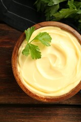 Delicious mayonnaise sauce with parsley in bowl on wooden table, top view