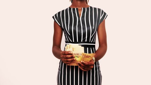young Black African business woman lady female wearing striped dress standing counting Ugandan Shilling notes against white background