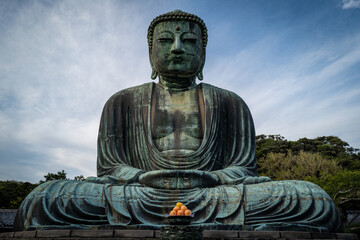 The Great Buddha of Kamakura sits peacefully under a partly cloudy sky, embodying serenity and spiritual contemplation.