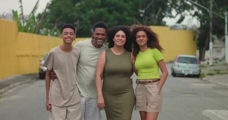 Close-knit family smiling and embracing outdoors in a friendly urban neighborhood, celebrating diversity and strong familial bonds with joyful expressions