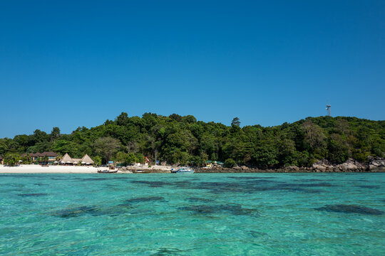 Serene tropical island beach resort with crystal-clear turquoise water and lush green foliage.