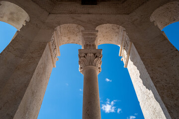 Majestic stone column framed by arches reaches towards a brilliant blue sky, a testament to...