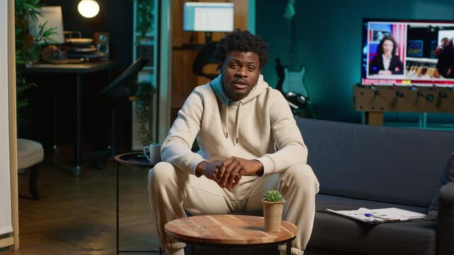 Black male student trying to learn a new language from his living room, attending an online course lesson to develop his skills. Ambitious person solving exercises and tasks remotely. Camera A.