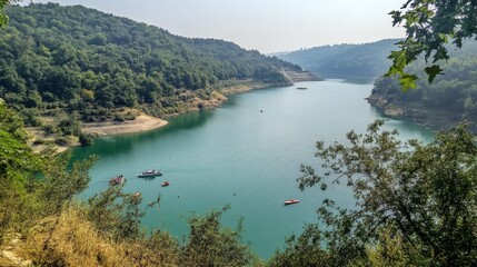 Obraz premium Serene Lake Surrounded by Lush Green Hills in Bright Daylight