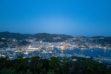 Night view of Nagasaki, Japan: City lights illuminate the harbor and surrounding hills, creating a stunning nocturnal cityscape.