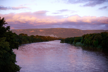 Forest, lake and mountain outdoor at sunset for travel, holiday or vacation location with sky. Woods, river and water with landscape environment, clouds and ecosystem with trees for tourism in Chile