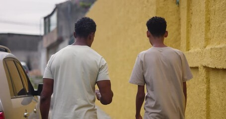 Father and son of African descent walking side by side on a quiet urban street, sharing a meaningful conversation, highlighting parenting and mentoring connection