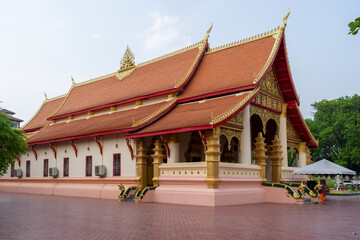 Stunning Lao temple with a vibrant red roof, intricate golden details, and serene atmosphere.