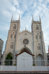 Obraz premium The majestic Church of St. Francis Xavier in Malacca, Malaysia, stands tall under a partly cloudy sky, showcasing its stunning architectural details.