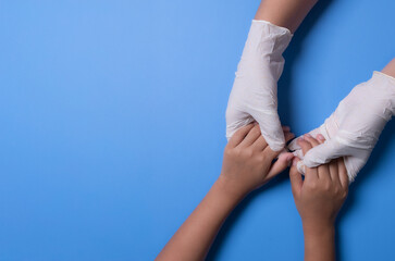 Obraz premium Doctor holding child's hand on blue background. View from above. Copy space