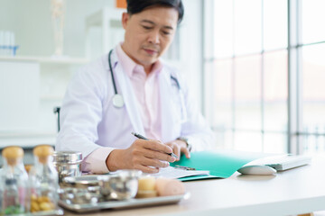 Asian doctor is working on a documents and papers report in the office in hospital.