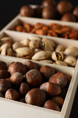 Wooden box with different nuts on a dark background