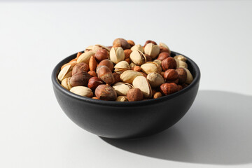 Assorted nuts in a black bowl on a white background