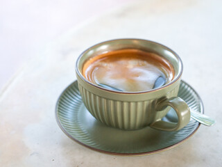 Hot black coffee in green cup and saucer.