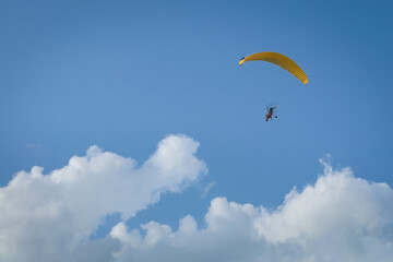 Paramotor flying in blue sky. Extreme leisure sports. Copy space.