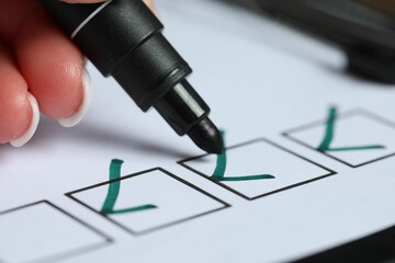 Woman checking box of paper form at table, closeup
