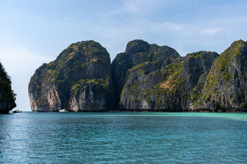 Naklejka premium Serene tropical bay with dramatic cliffs and turquoise water, perfect for a relaxing getaway.