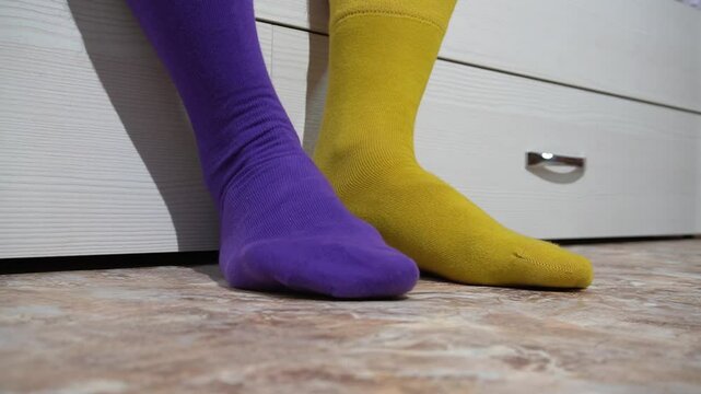 Mismatched socks in bright purple and yellow colors symbolize individuality and self-expression. Day of unpaired socks.