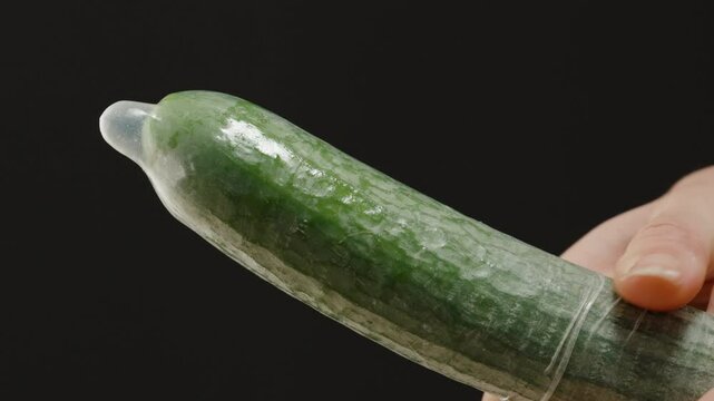 A Woman Demonstrating Condom Placement and Proper Tip Fit on a Cucumber During a Sex Education Lesson
