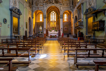 Fototapeta premium Sunlight streams through the high windows of this empty church, illuminating the rows of pews and the altar in the background.