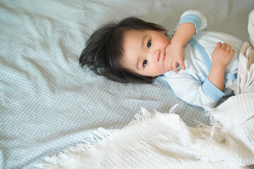 Cute baby is resting on a comfortable bed.