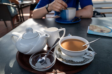 A perfect moment: enjoying tea with milk and sugar at a sunny outdoor cafe.