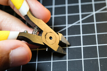Closeup of fingers holding stainless nipper for cutting plastic. Black Cutting mat background with white lines. The concept of a master model kits hobby. Negative space. Sharp pliers