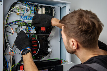 Technician working on internal wiring of heat pump, inspecting electrical connections. Specialist...