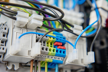 Colorful wires and components connected to terminal block in distribution box. Electrical circuit...