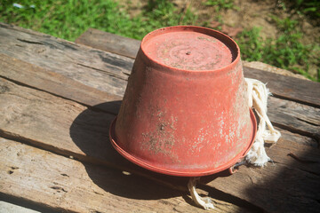 Old red tin can on wooden table with green grass in background.
