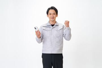 携帯を持ちカメラ目線の作業着を着た男性