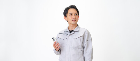 携帯を持つ作業着を着た男性