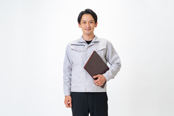 カメラ目線のファイルを持つ作業着を着た男性