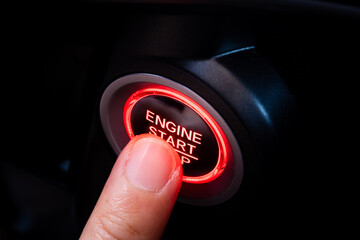 The driver's hand is pressing the car start button. Concept of transportation and technology	