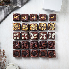 A tempting variety of brownies with different toppings arranged in a perfect square on a light background, showcasing rich textures and colors
