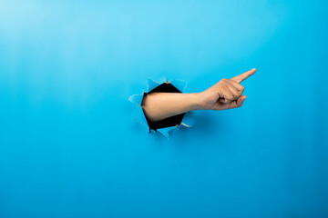 Human hand showing from ripped paper. Hand gestures of pointing or counting. Mockup or Copy space. Concept of sign or communication