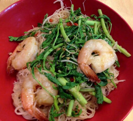 Stir-fried rice noodles with shrimp and water mimosa in red bowl